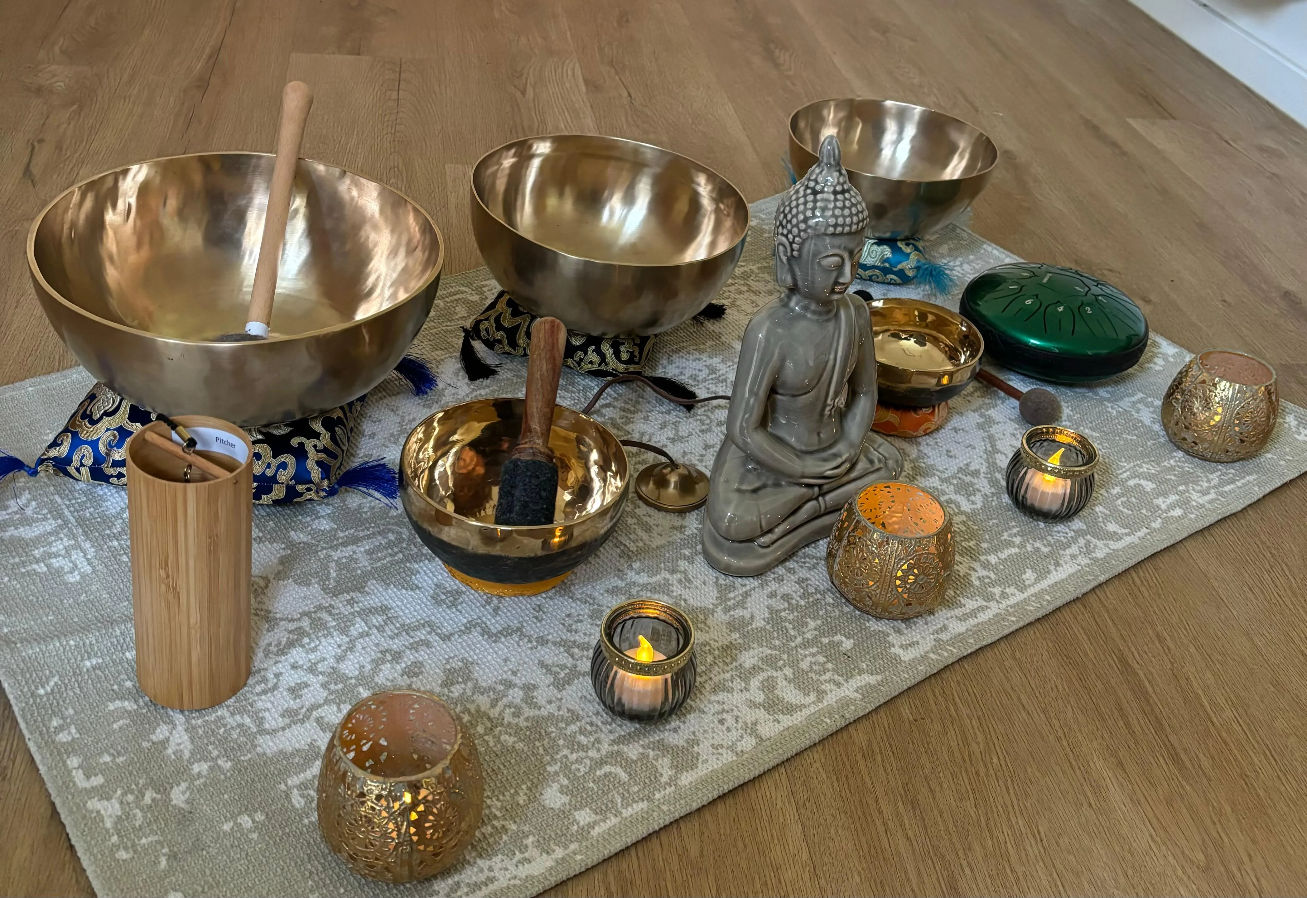 Eine Auswahl an Klangschalen, Buddha-Figur und Kerzen, vorbereitet für eine Klang-Auszeit